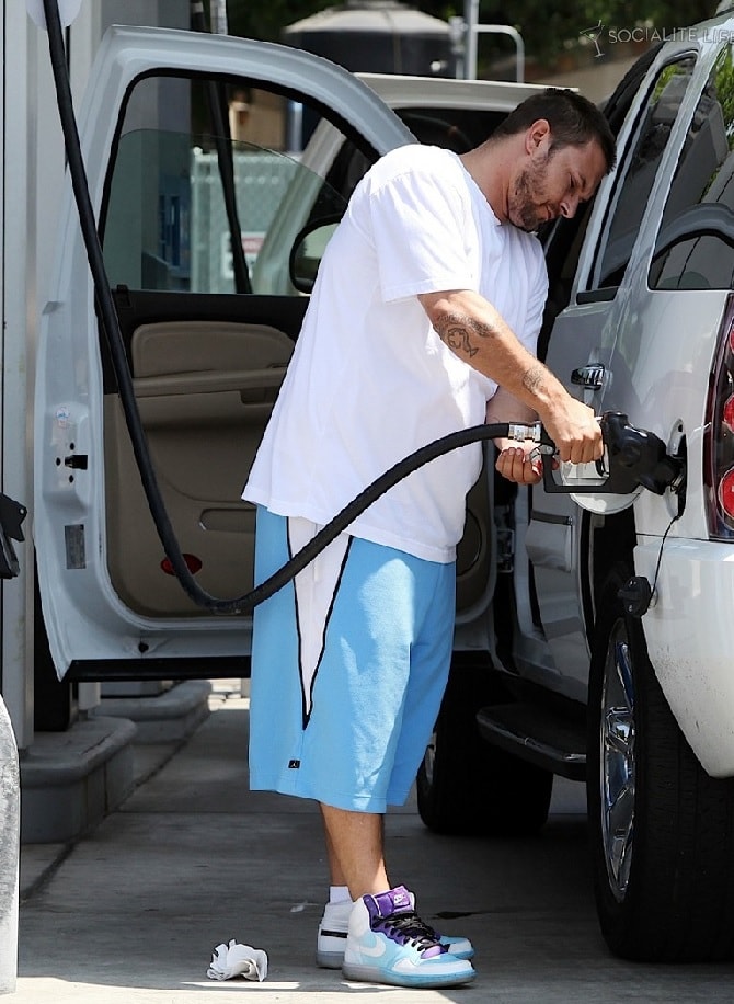 Kevin Federline standing in his white t-shirt and blue half pant while filling his white cars tank
